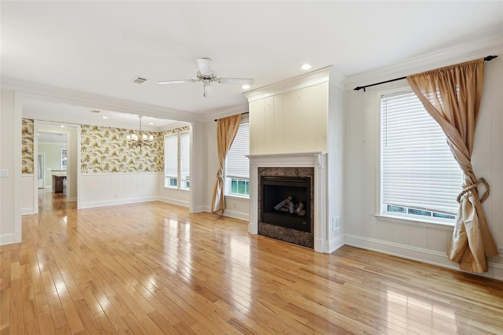 A living room with hardwood floors, a fireplace, and an adjacent dining area with wallpaper — 11604 SE SHELFER AVENUE, ARCADIA, FL