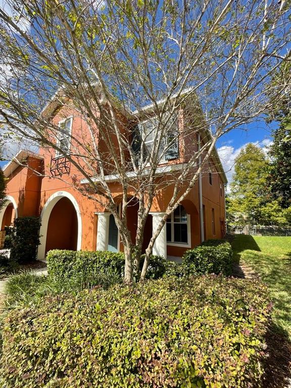 A two-story orange stucco house with arched entryways and a large tree in the front — 10934 JOHANNA AVENUE, RIVERVIEW, FL