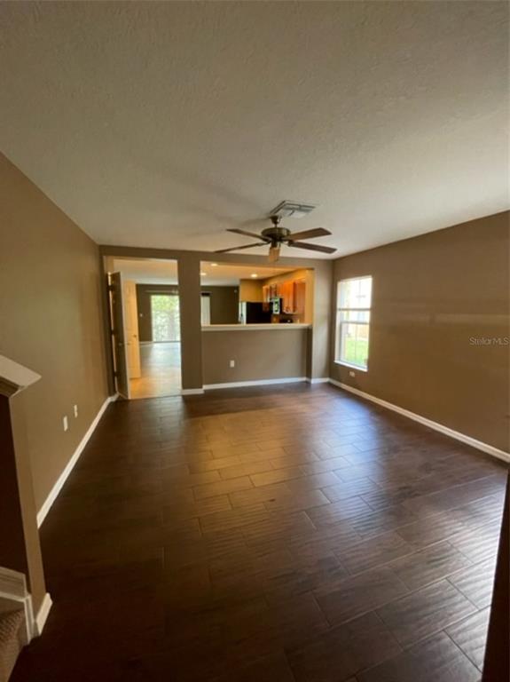 A living room with dark wood-look tile flooring, a ceiling fan, and an open kitchen — 10934 JOHANNA AVENUE, RIVERVIEW, FL