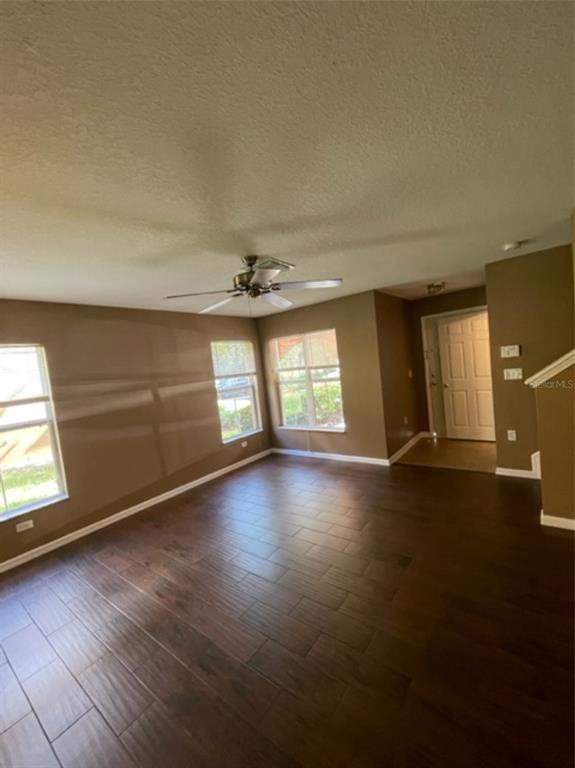 A living room with dark wood-look tile flooring, a ceiling fan, and three windows — 10934 JOHANNA AVENUE, RIVERVIEW, FL