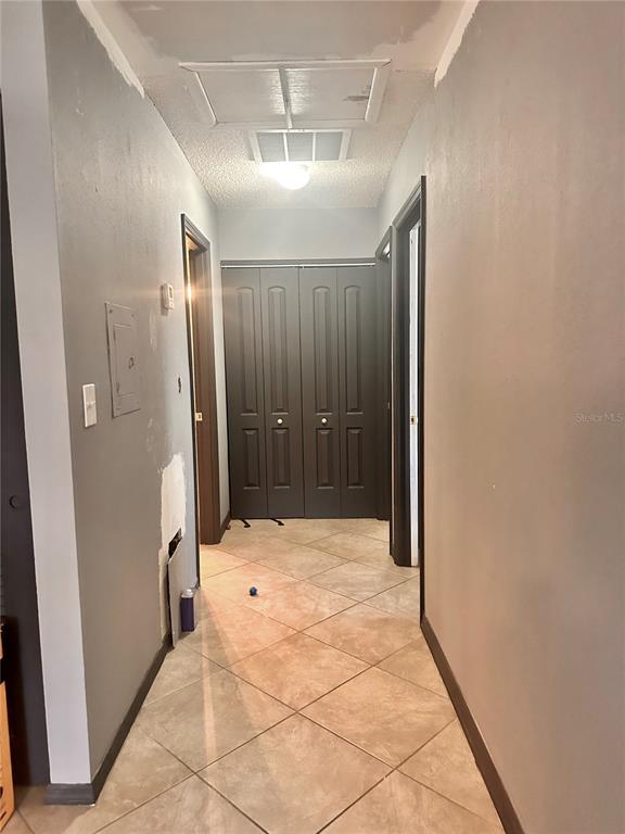 A hallway with gray walls, tile flooring, and dark bifold closet doors at the end — 2938 CLARK ROAD UNIT 203, SARASOTA, FL