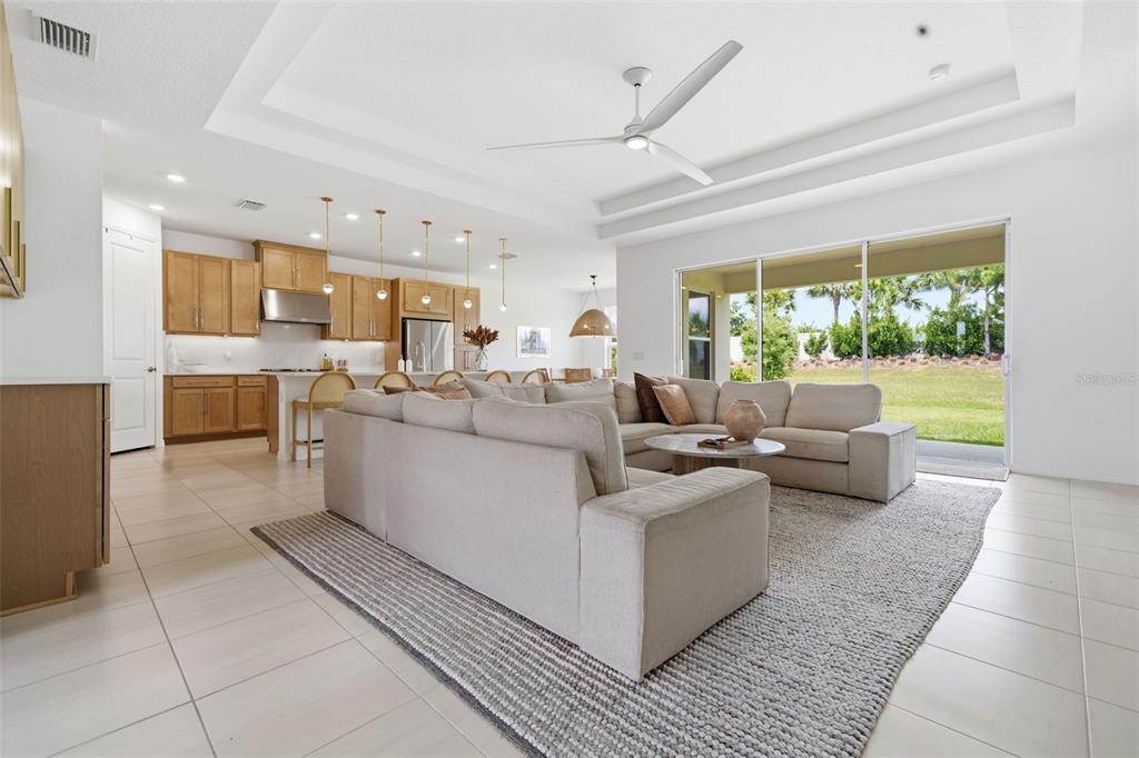 A bright open-concept living room and kitchen featuring light wood cabinetry and a large sectional — 16508 STAR GRASS CIRCLE, BRADENTON, FL