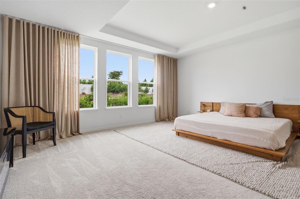A bedroom features a low wooden platform bed, beige curtains, and a cane-back chair — 16508 STAR GRASS CIRCLE, BRADENTON, FL