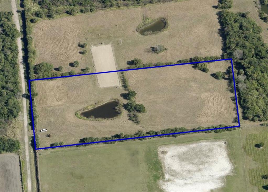 An aerial view shows a rectangular plot of land featuring a riding arena and pond — 0 ORLANDO AVENUE, MIMS, FL