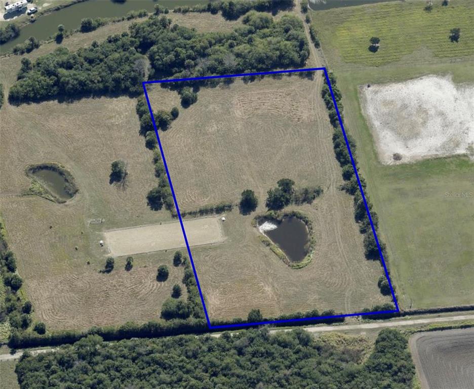 An aerial view shows a rectangular plot of land featuring a pond and open fields — 0 ORLANDO AVENUE, MIMS, FL