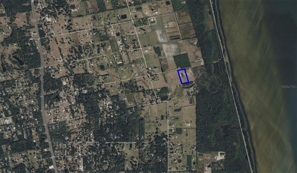 An aerial view shows a rectangular plot of land outlined in blue near a lake — 0 ORLANDO AVENUE, MIMS, FL