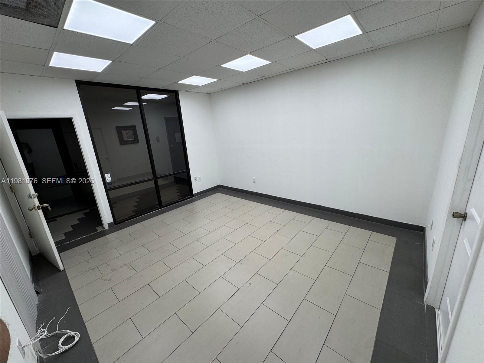An empty office room features light-colored tile flooring, white walls, and a glass-paneled wall partition — 900 W 49th St Suite 538, Hialeah FL 33012, HIALEAH, FL