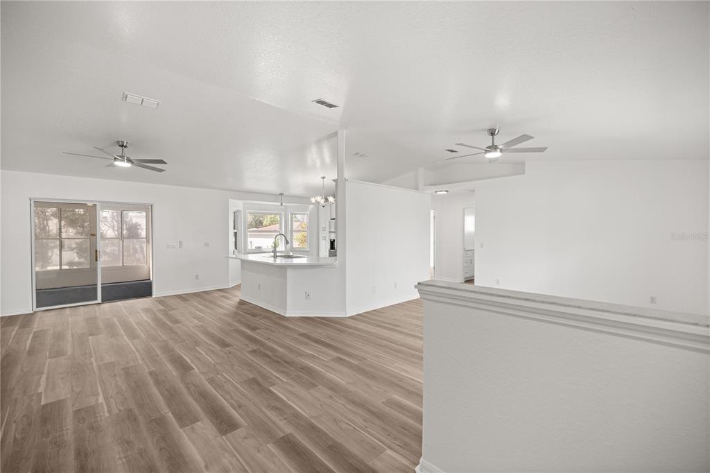 An open-concept living area features light wood-look flooring, white walls, and two ceiling fans — 9920 SW 63RD COURT, OCALA, FL