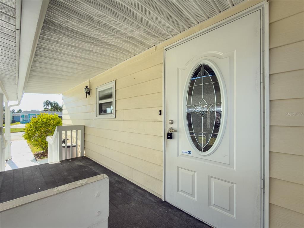 A white front door with an oval glass insert sits on a covered porch — 47 QUAIL COURT, ELLENTON, FL