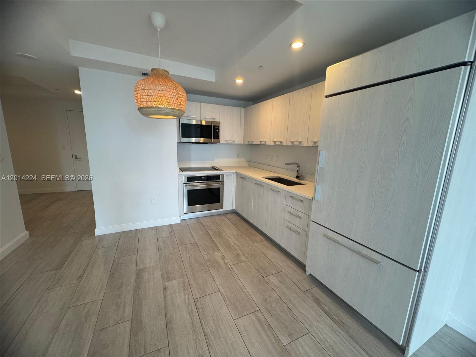 A modern kitchen features light wood-grain cabinets, stainless steel appliances, and wood-look tile flooring — 45 SW 9th St # 1104, Miami FL 33130, MIAMI, FL