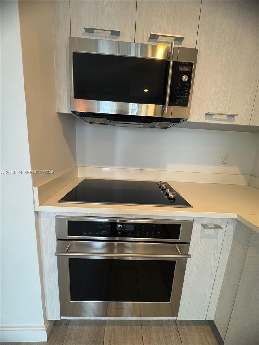 A kitchen features a stainless steel microwave, oven, and a black glass cooktop — 45 SW 9th St # 1104, Miami FL 33130, MIAMI, FL