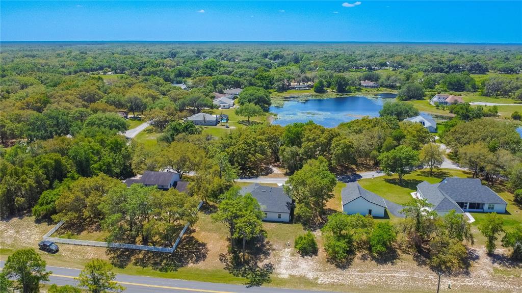 An aerial view shows several houses surrounded by trees and a small lake — 9695 E BAYMEADOWS DRIVE, INVERNESS, FL