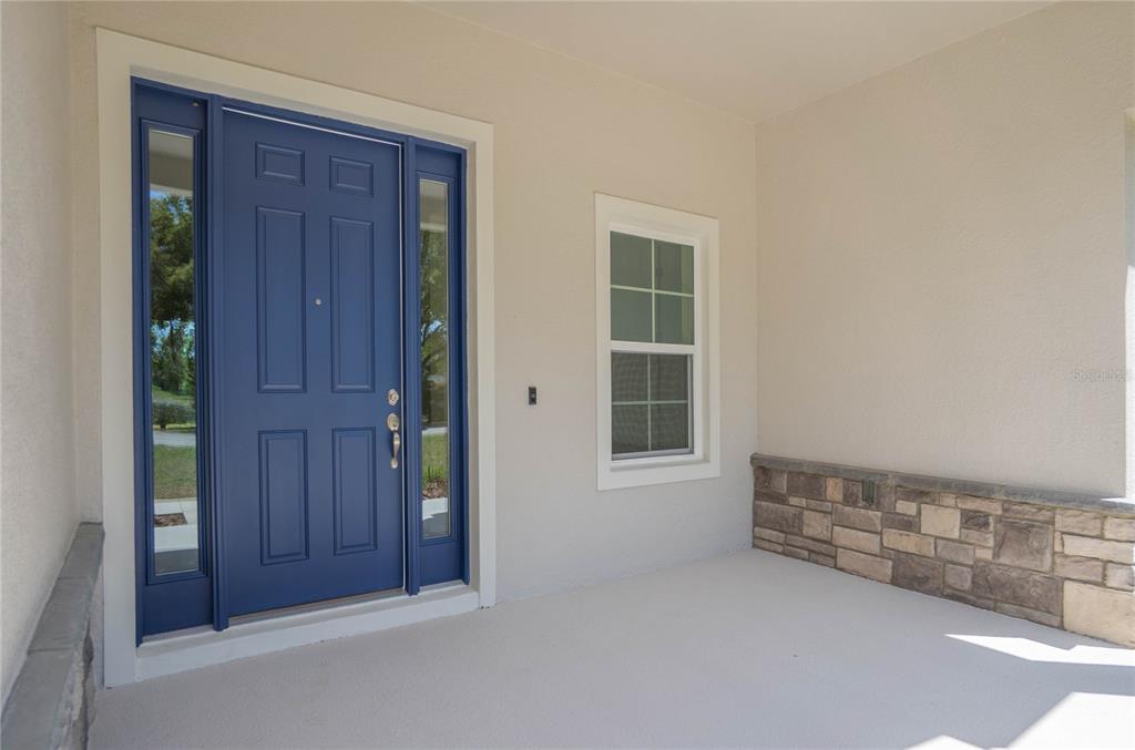 A front porch features a blue door with sidelights, a window, and stone veneer accents — 9695 E BAYMEADOWS DRIVE, INVERNESS, FL