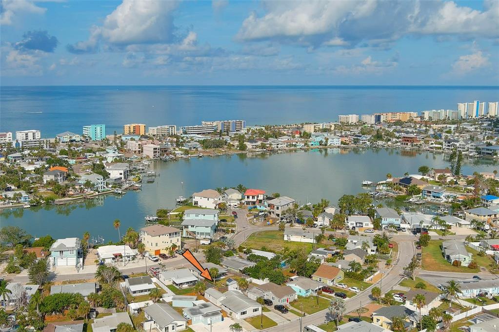 An aerial view of a coastal neighborhood with an orange arrow pointing to a house — 14036 MARGUERITE DRIVE, MADEIRA BEACH, FL