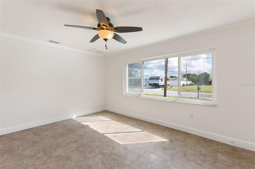 An empty room with white walls, tile flooring, a ceiling fan, and a large window — 14036 MARGUERITE DRIVE, MADEIRA BEACH, FL