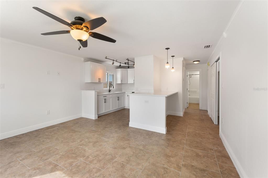 An open-concept kitchen and living area features white cabinetry, a breakfast bar, and tile flooring — 14036 MARGUERITE DRIVE, MADEIRA BEACH, FL