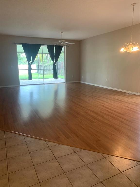 A living area features wood flooring, a ceiling fan, and sliding glass doors to the backyard — 19132 WOOD SAGE DRIVE, TAMPA, FL