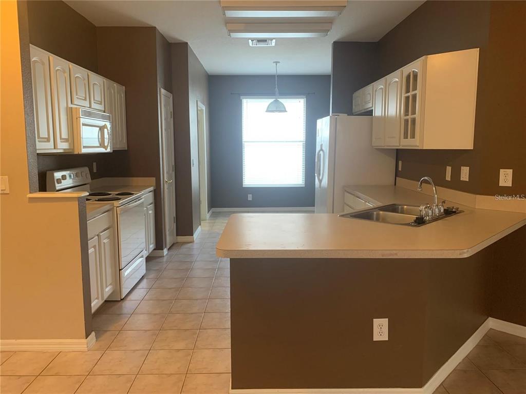 A kitchen with white cabinets, a breakfast bar, and a dining area with a window — 19132 WOOD SAGE DRIVE, TAMPA, FL