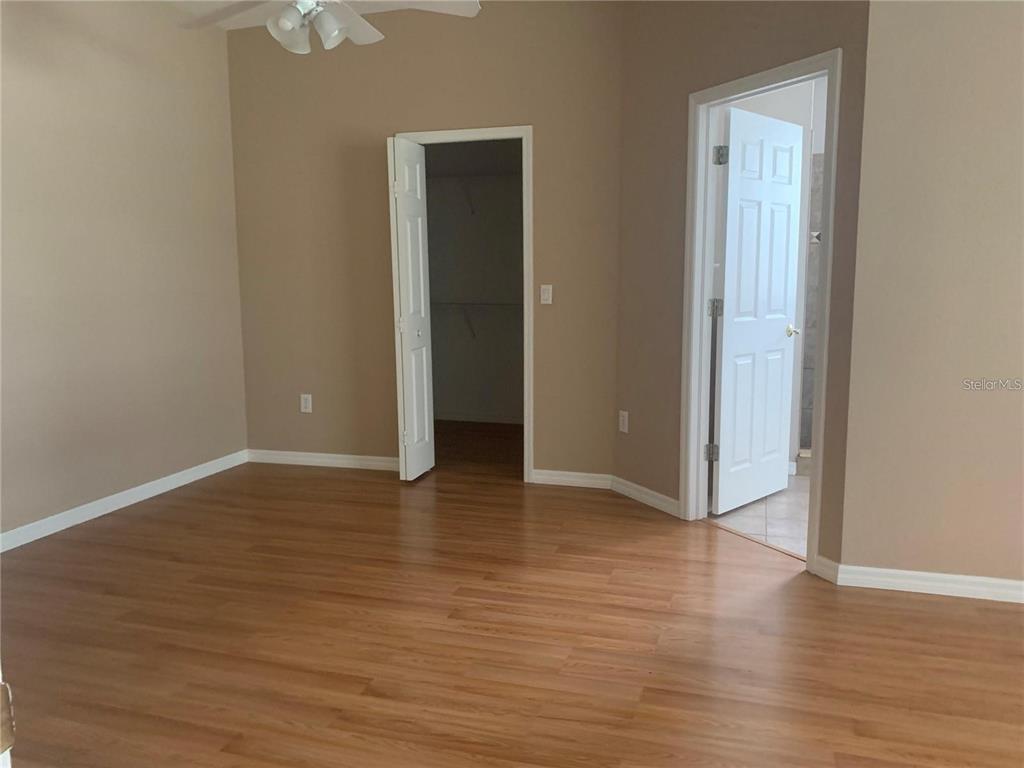 A bedroom with wood-look flooring, a walk-in closet, and an attached bathroom — 19132 WOOD SAGE DRIVE, TAMPA, FL