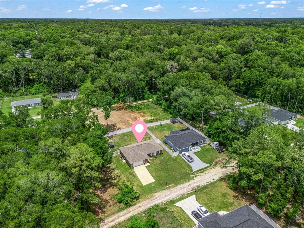 An aerial view shows a single-story house with a driveway surrounded by trees and lots — 4243 SE 131ST LANE, BELLEVIEW, FL