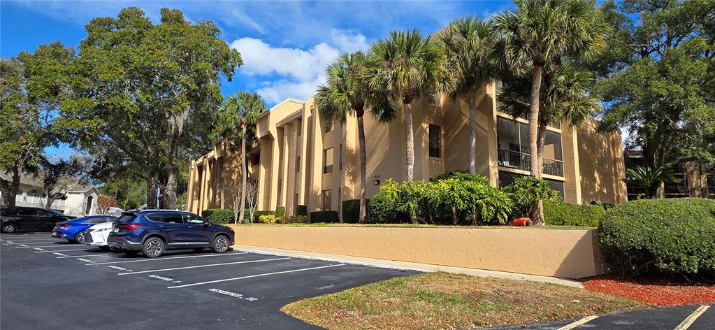 A multi-story tan apartment building with palm trees and a parking lot in front — 630 CRANES WAY UNIT 203, ALTAMONTE SPRINGS, FL