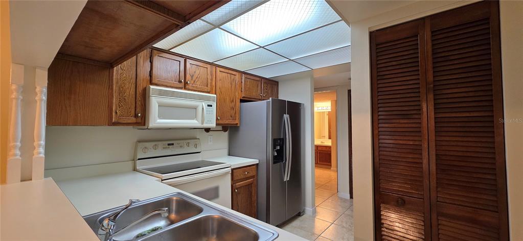 A kitchen features wood cabinets, white appliances, a double sink, and a drop ceiling — 630 CRANES WAY UNIT 203, ALTAMONTE SPRINGS, FL