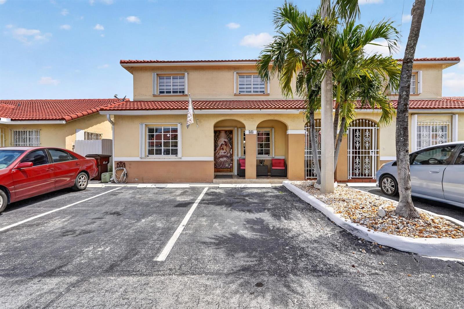 A two-story yellow townhouse with a red tile roof and two parking spaces in front — 7101 W 24th Avenue # 45, Hialeah FL 33016, HIALEAH, FL