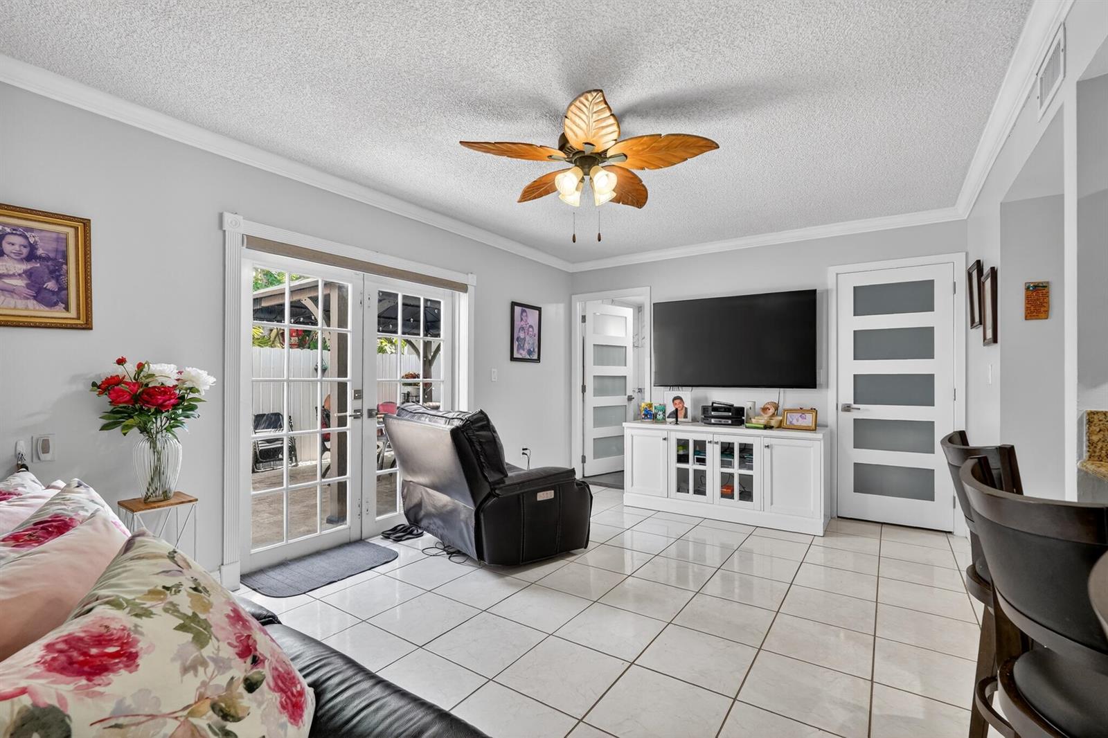 A living room features white tile floors, a leaf-shaped ceiling fan, and glass-paneled doors — 7101 W 24th Avenue # 45, Hialeah FL 33016, HIALEAH, FL