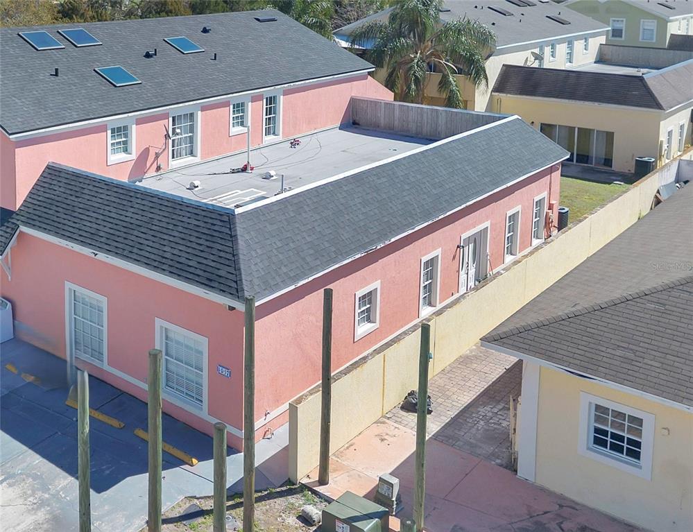 A pink exterior wall features two windows and parking spaces with yellow concrete bumpers — 1057 UNIVERSAL REST PLACE, KISSIMMEE, FL