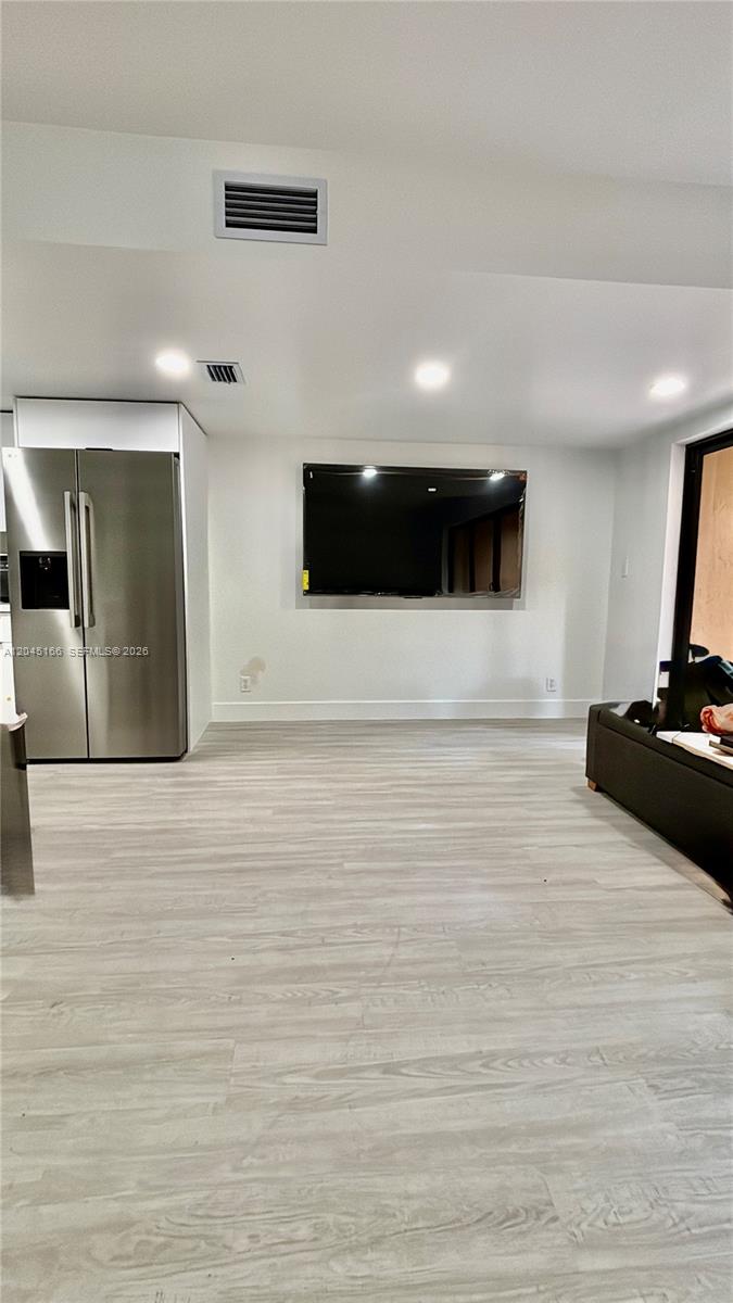 A room with light wood-look flooring, a stainless steel refrigerator, and a wall-mounted television — 8010 NW 27th Pl # 8010, Sunrise FL 33322, SUNRISE, FL