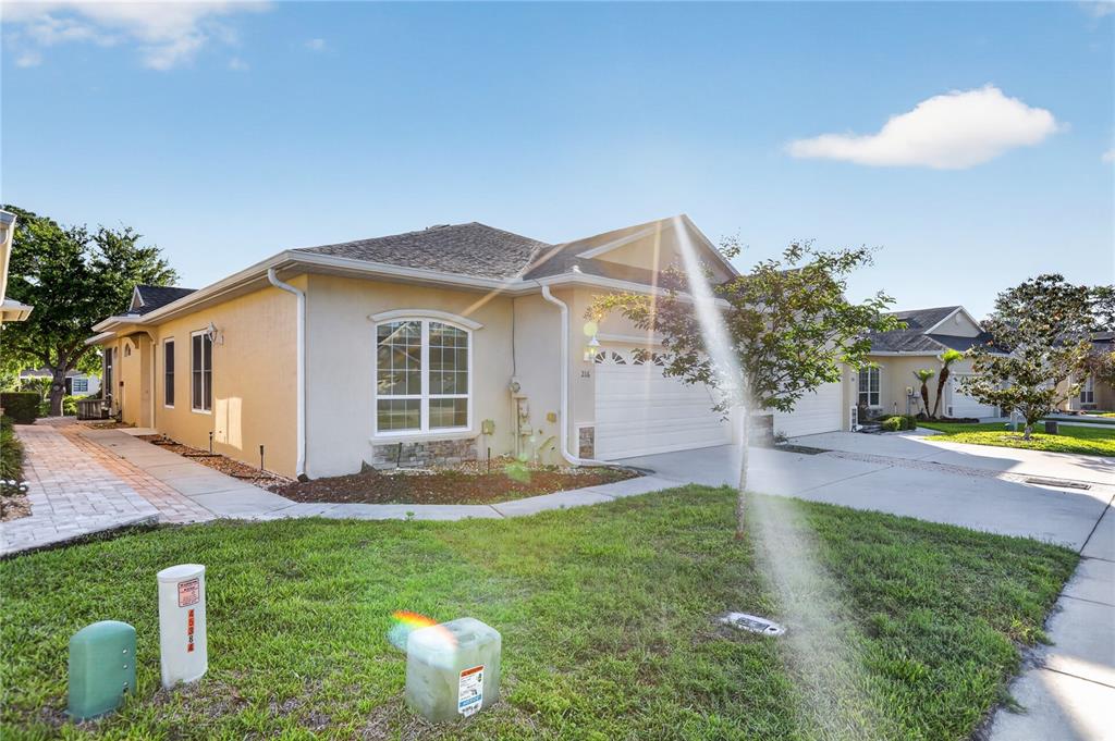 A single-story house with a beige stucco exterior, a two-car garage, and a paved walkway — 216 LAMONTE POINT COURT, DEBARY, FL