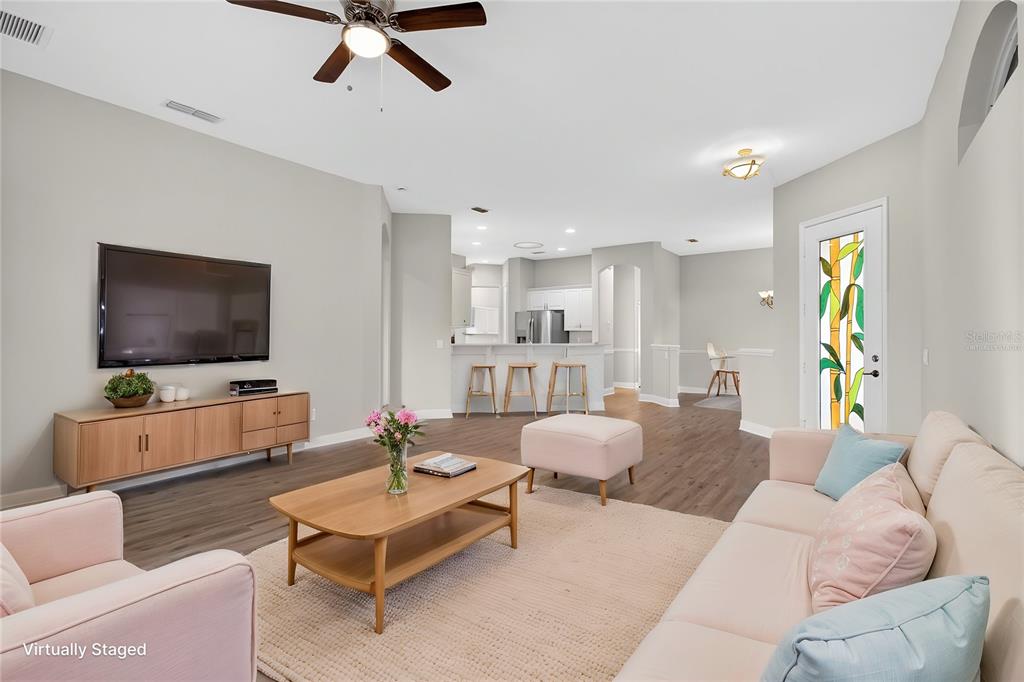 A living room with light wood flooring, a ceiling fan, and a kitchen in the background — 216 LAMONTE POINT COURT, DEBARY, FL