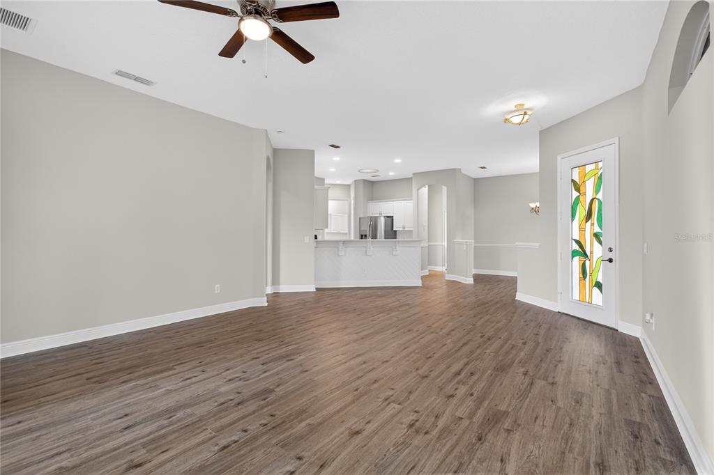 An open-concept living area features wood-look flooring, a ceiling fan, and a glass-paneled door — 216 LAMONTE POINT COURT, DEBARY, FL