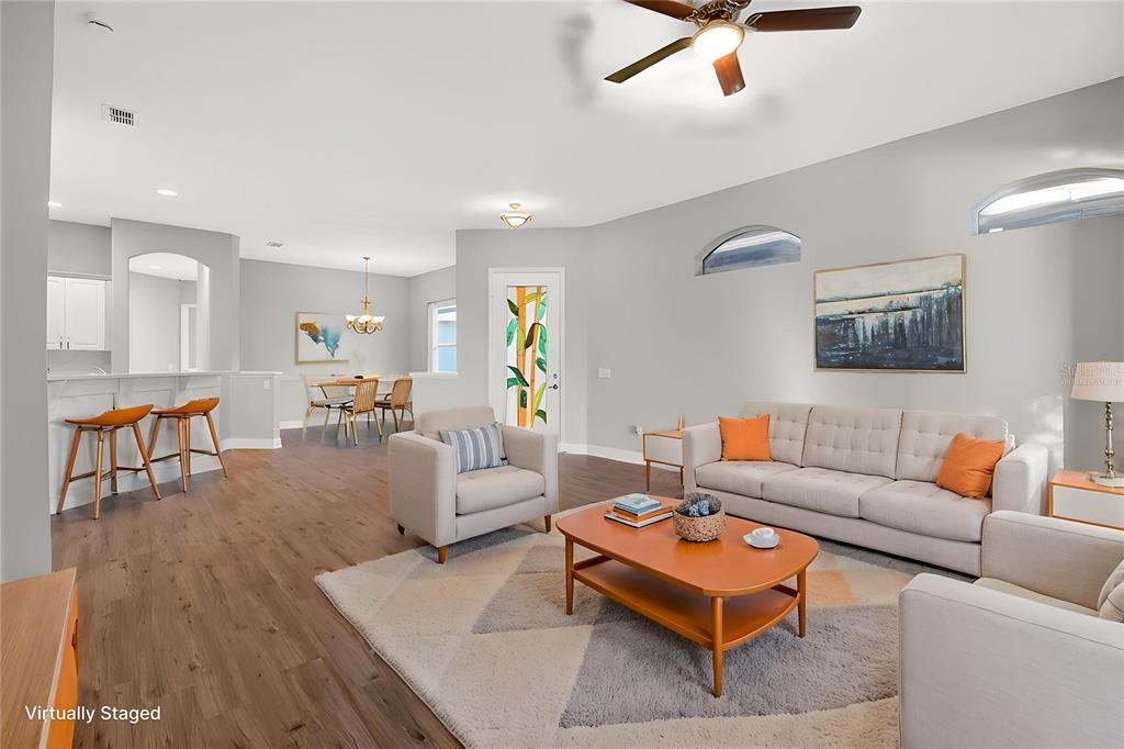 A living room with light wood floors, a beige sofa, and an adjacent dining area — 216 LAMONTE POINT COURT, DEBARY, FL