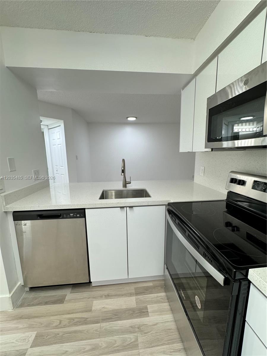 A kitchen features white cabinets, stainless steel appliances, and light-colored countertops — CORAL SPRINGS, FL