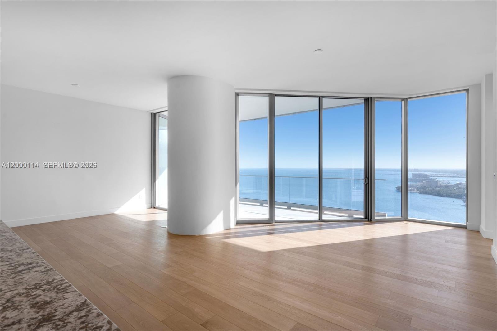 An empty room with light wood floors, a structural column, and floor-to-ceiling windows overlooking water — 175 SE 25 RD # 3003, Miami FL 33129, MIAMI, FL