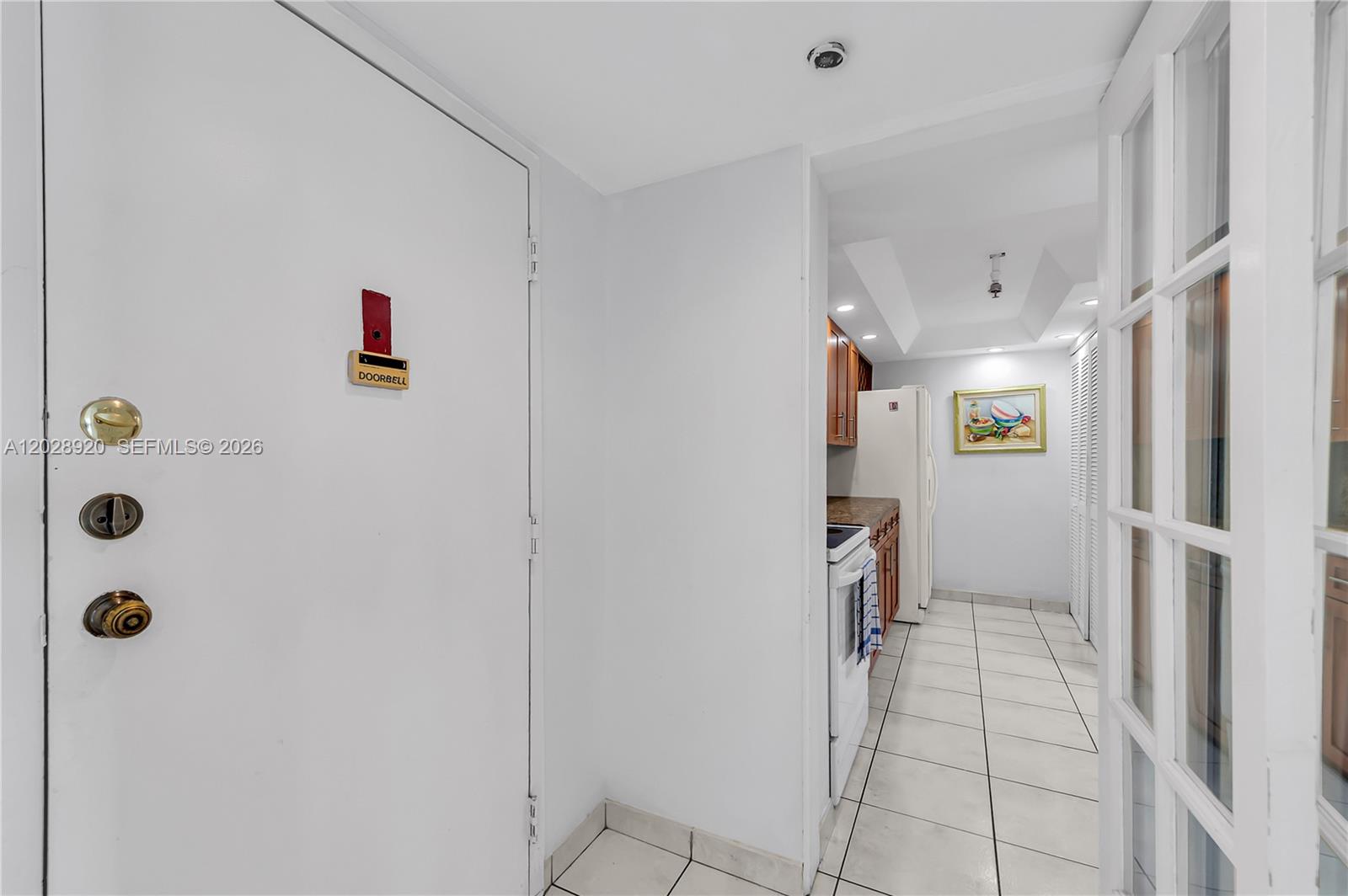 A white door with a doorbell sign opens into a tiled kitchen area — 3200 Collins Ave # 8, Miami Beach FL 33140, MIAMI BEACH, FL
