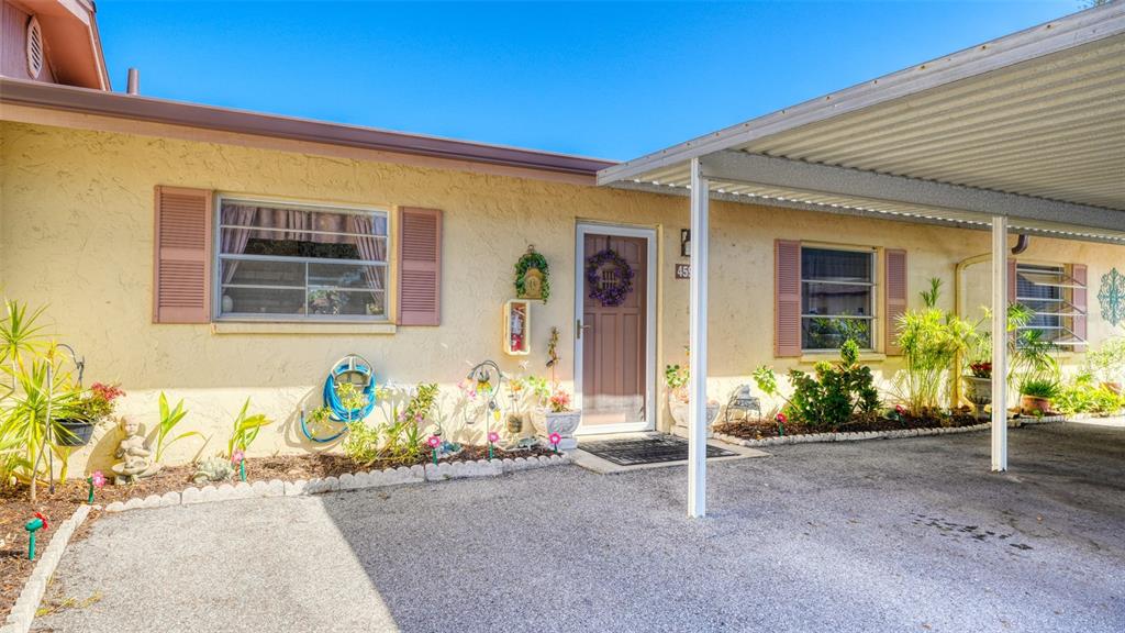 A single-story house with a carport, stucco exterior, and a front garden bed — 4591 MOHICAN TRAIL UNIT 137, SARASOTA, FL