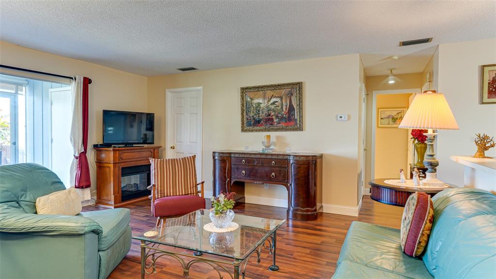 A living room features a teal sofa, a glass coffee table, and a wooden fireplace — 4591 MOHICAN TRAIL UNIT 137, SARASOTA, FL