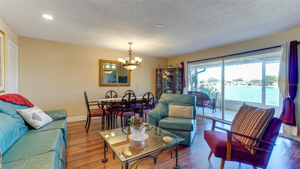 A living and dining room with wood floors, a glass coffee table, and waterfront views — 4591 MOHICAN TRAIL UNIT 137, SARASOTA, FL