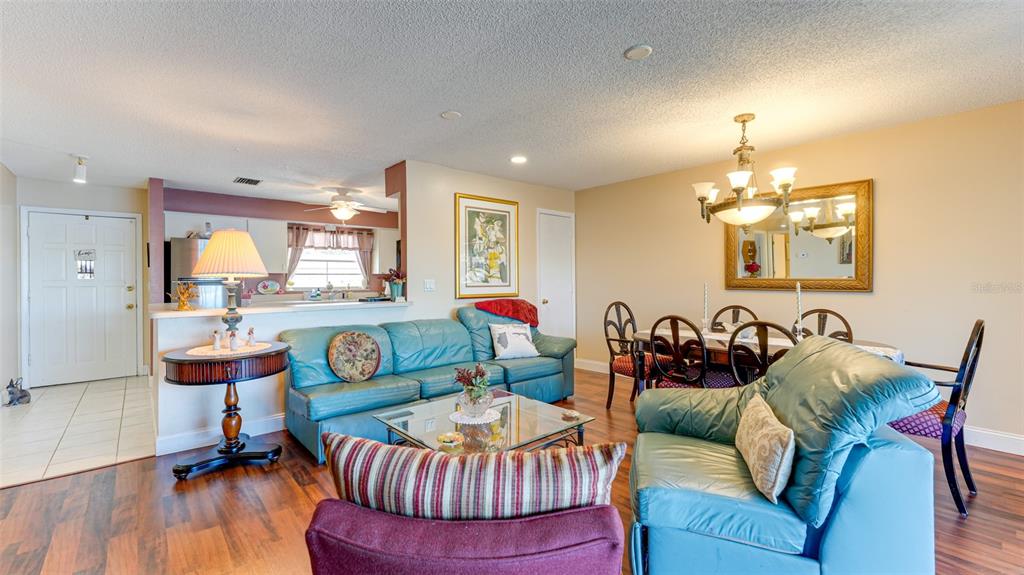 A living and dining area features blue leather furniture, wood flooring, and a chandelier — 4591 MOHICAN TRAIL UNIT 137, SARASOTA, FL