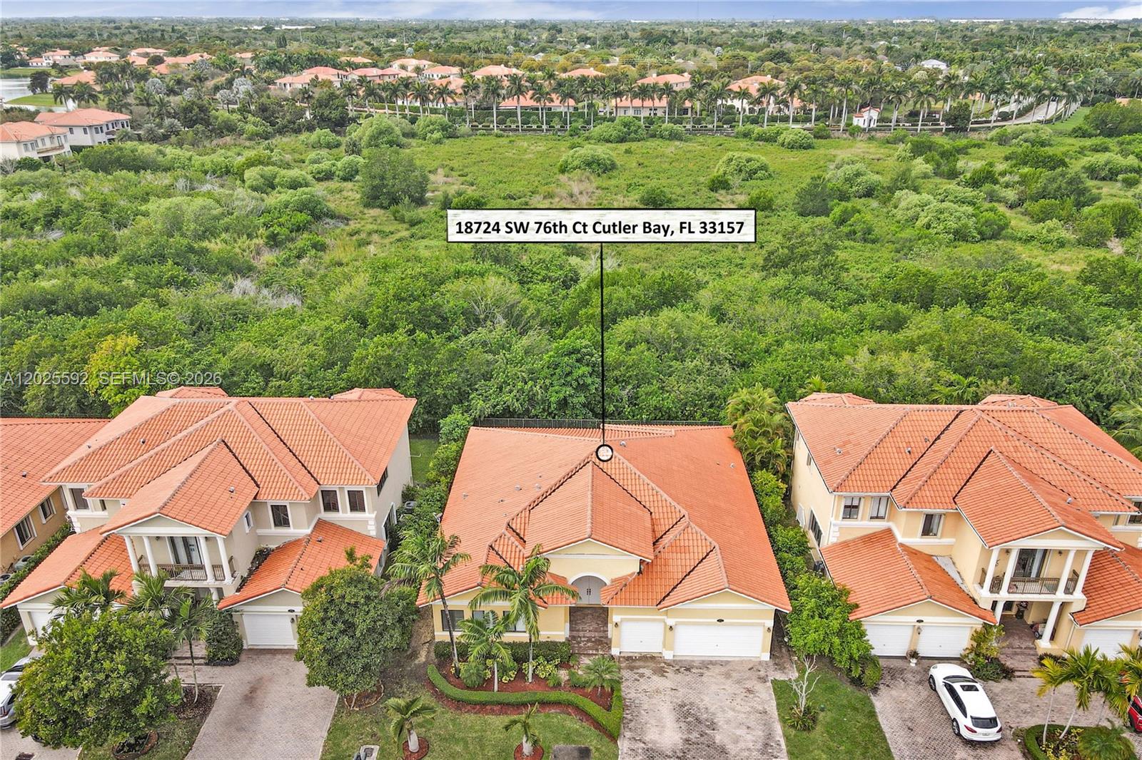 An aerial view shows a single-family home with a red tile roof surrounded by dense vegetation — CUTLER BAY, FL