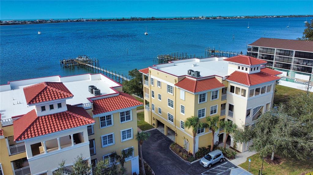 An aerial view shows two yellow multi-story apartment buildings with red tile roofs near water — 1116 S MCCALL ROAD UNIT 121, ENGLEWOOD, FL