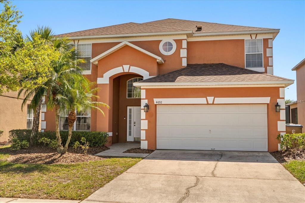 A two-story house with orange stucco siding, white trim, and an attached two-car garage — 4692 GOLDEN BEACH COURT, KISSIMMEE, FL