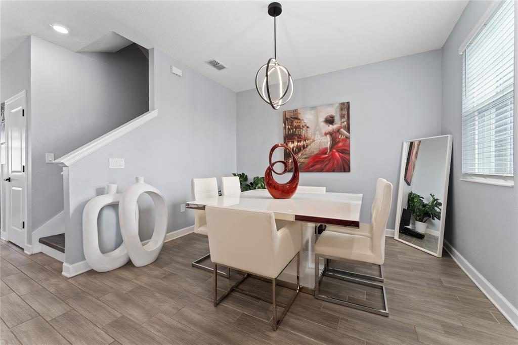 A dining room features a white table, four chairs, a red sculpture, and a floor mirror — 14095 TITLE WAY, WINTER GARDEN, FL