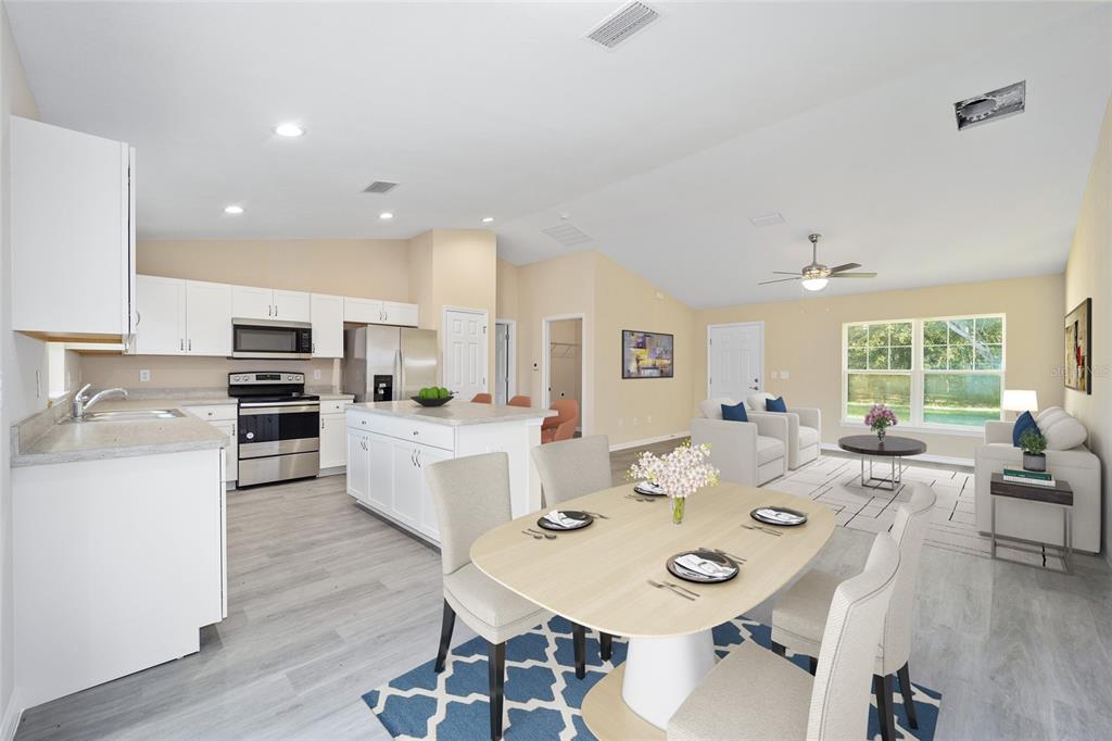 An open-concept kitchen, dining area, and living room with white cabinets and light wood flooring — 14162 SW 16TH PLACE, DUNNELLON, FL