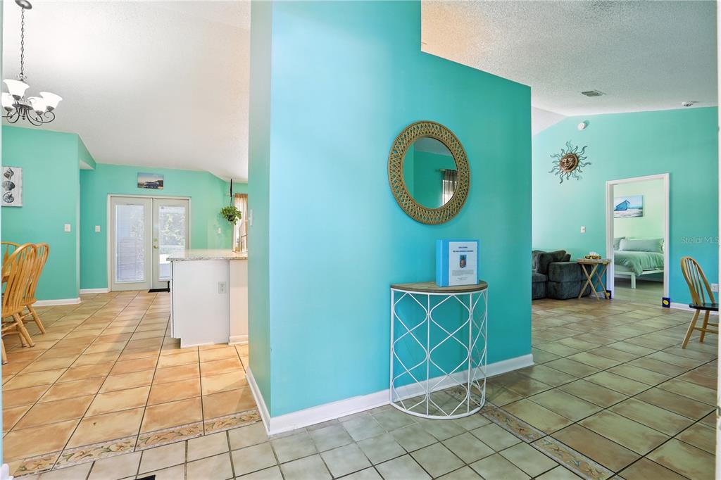 A turquoise entryway features a round mirror, a white metal console table, and tile flooring — 818 WIL O WIK DRIVE, CASSELBERRY, FL