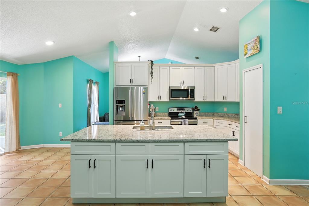 A kitchen with light blue cabinets, a granite-topped island, and turquoise walls — 818 WIL O WIK DRIVE, CASSELBERRY, FL