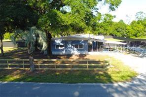 An exterior view of a blue single-story house with a carport and a wooden fence — 8047 CINDY DRIVE, ZEPHYRHILLS, FL