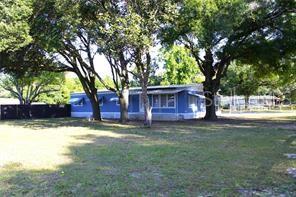 A blue mobile home sits on a grassy lot shaded by several large trees — 8047 CINDY DRIVE, ZEPHYRHILLS, FL
